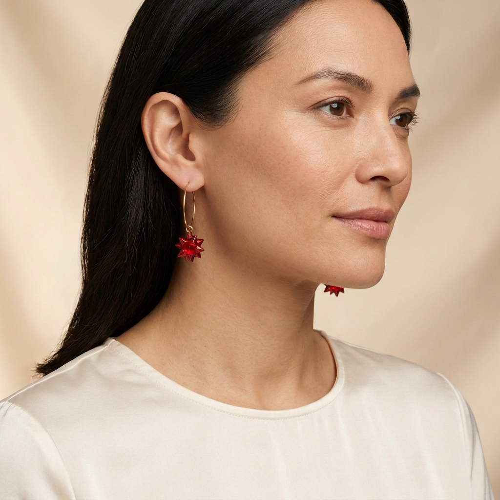 Model wearing hoop earrings with petite red starburst charms