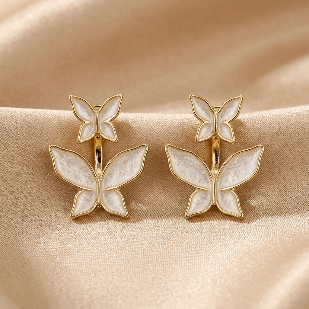 Compact double-butterfly ear jacket earrings with ivory-white wings and gold-tone outlines