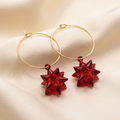 Red starburst charm hoop earrings on champagne satin