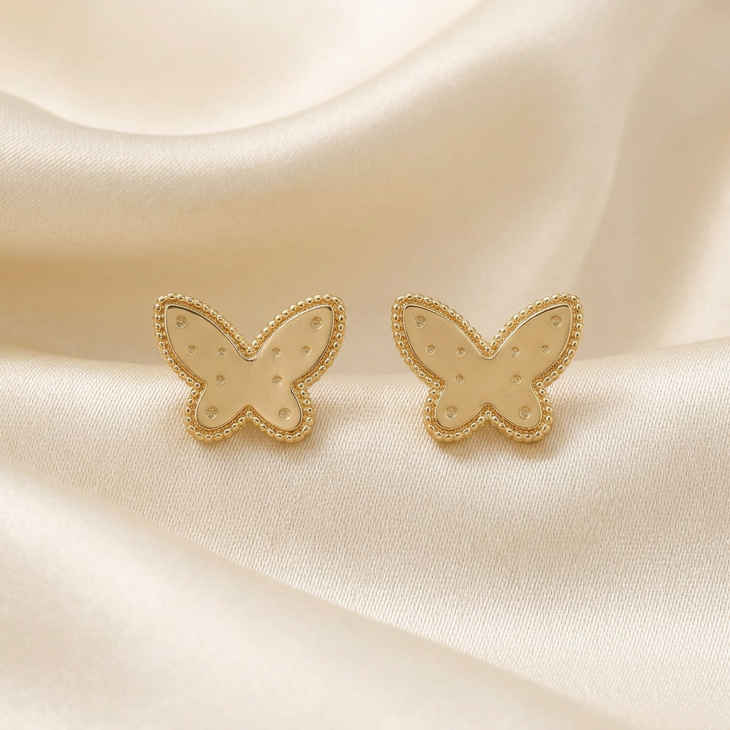 Gold butterfly stud earrings matched to the actual product on ivory satin