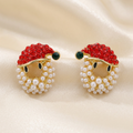 Santa face stud earrings with red stone hats, green pom-poms, and white pearl-like beards on ivory satin