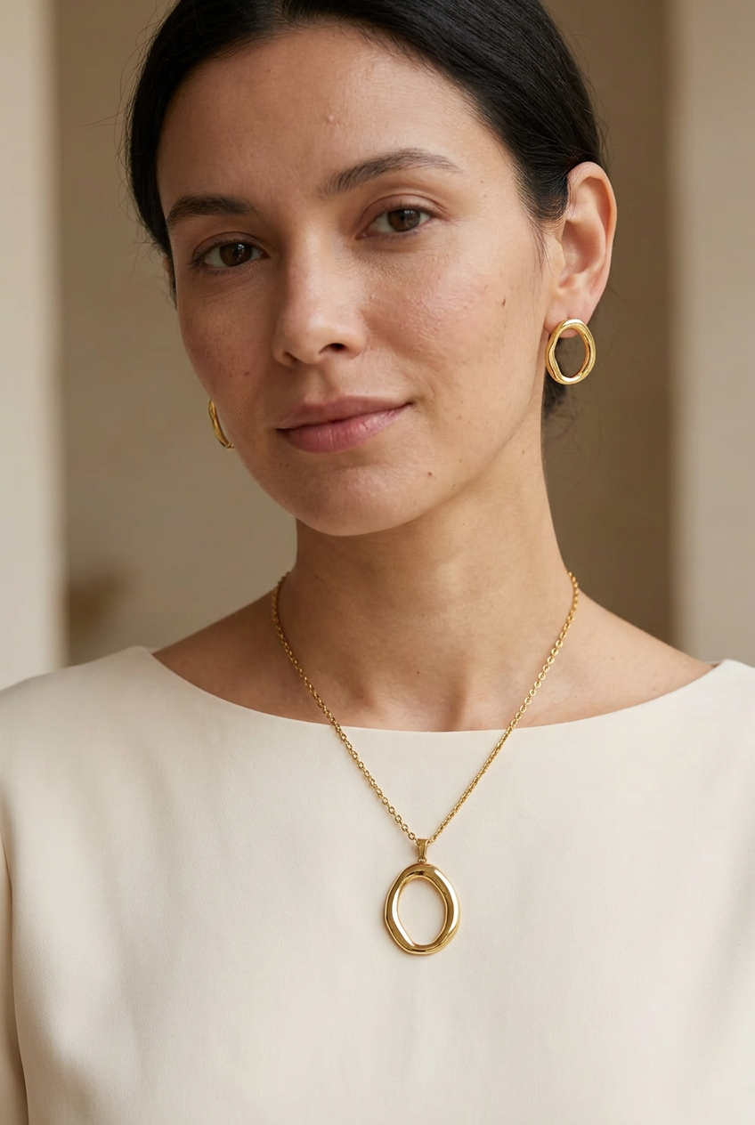 Model wearing the gold-tone oval pendant necklace and matching earrings