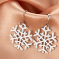 White openwork snowflake drop earrings on champagne satin