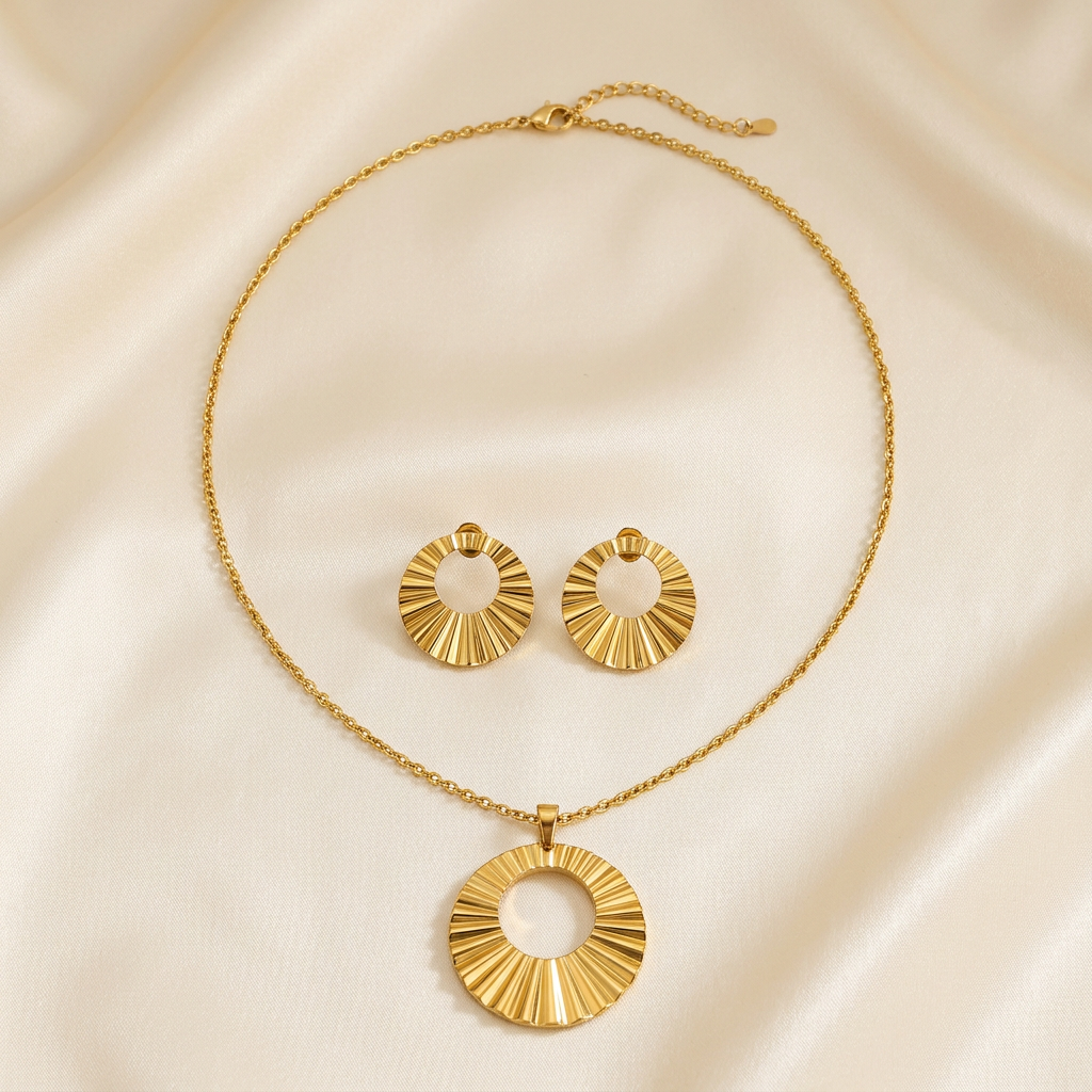 Gold-tone open circular sunburst necklace and matching pleated earrings on ivory satin