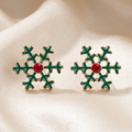 Pair of green enamel snowflake studs with red centre stones on ivory satin