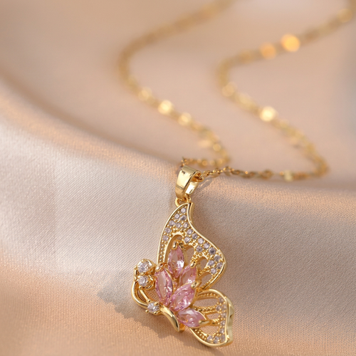 Gold-tone butterfly necklace with pink and clear stone accents on ivory satin