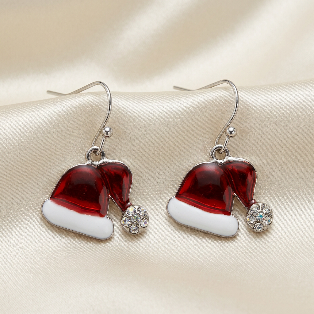 Red Santa hat drop earrings with white bands, rhinestone pom-poms, and silver-tone hooks on ivory satin