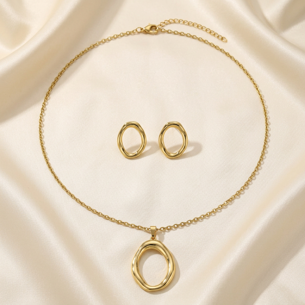 Gold-tone open oval pendant necklace and matching oval earrings on ivory satin